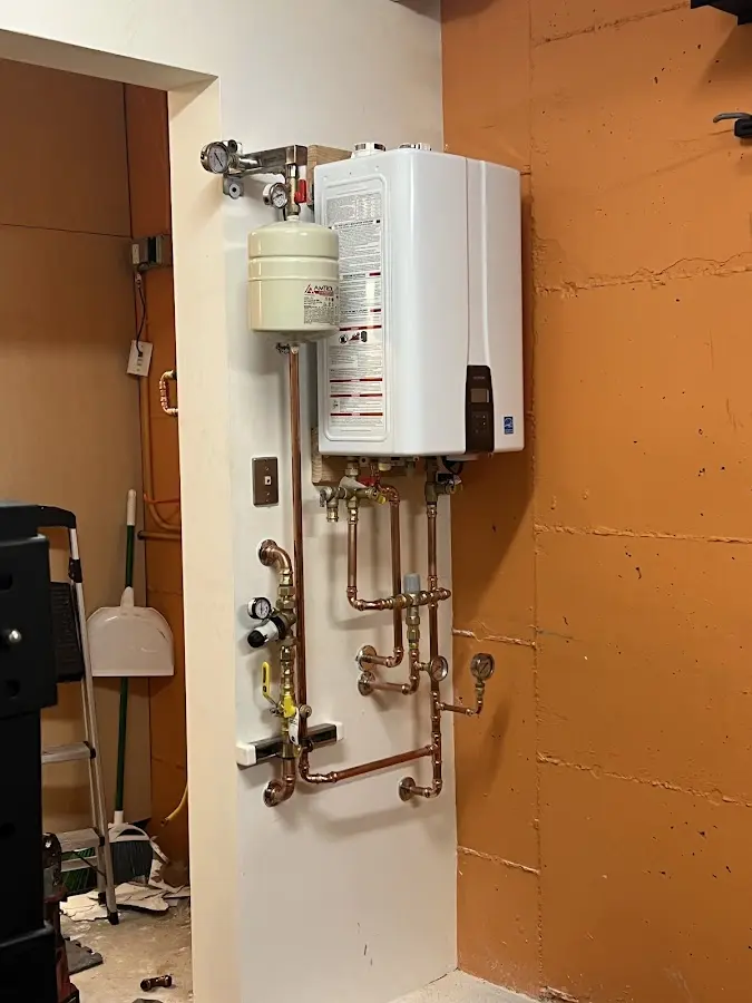 Plumbing technician inspecting water heater connections in Eastpointe